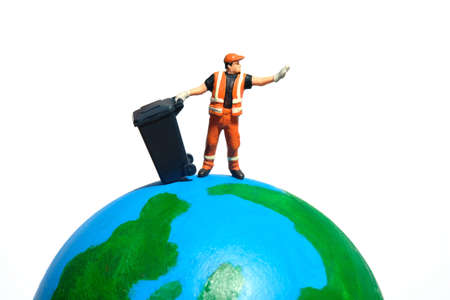 Cleaning worker with trash bin standing above earth globe. Global waste concept. Miniature people figure photographyの写真素材