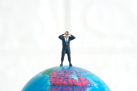Businessmen standing using binoculars above earth globe. Miniature tiny people toys photography. isolated on white background.の写真素材