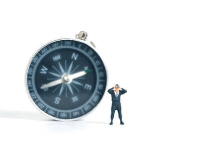 Businessmen standing using binoculars in front of compass. Miniature tiny people toys photography. isolated on white background.の写真素材
