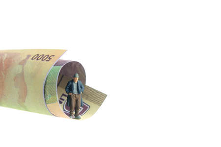 Poor man with no money left standing on rolled money paper. Miniature tiny people toys photography....