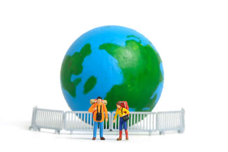 Miniature people toy photography. Travel ban concept, Backpacker and hiker traveller figure in front of globe and guardrail, isolated on white background. Image photoの写真素材