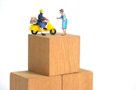 Miniature people toys conceptual photography. Post parcel package delivery. Postman courier with cardboard box, isolated on white backgroundの写真素材