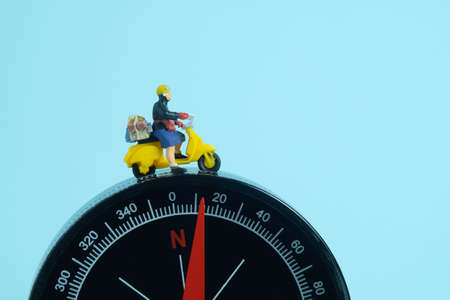 Miniature people toys conceptual photography. Address navigation. Postman courier with a compass,...