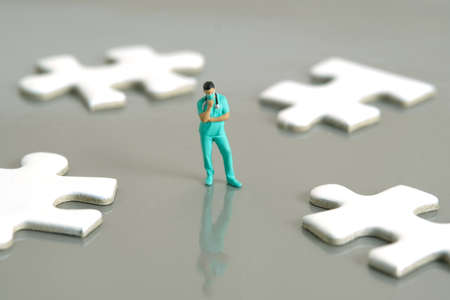 Miniature people toy figure photography. A men doctor or nurse thinking in the middle of four white...