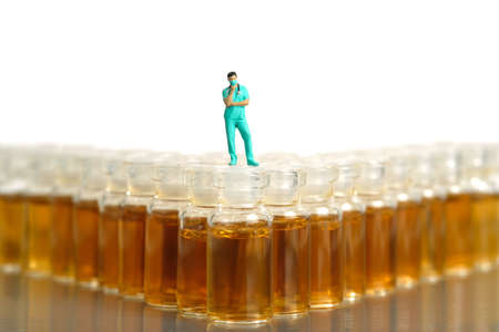 Miniature people toy figure photography. Miniature people toy figure photography. Vaccine alternative choice concept. A nurse standing above ampoule vial. Image photoの写真素材