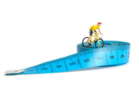 Miniature people toy figure photography. Fat burn concept. A biker cycling above measure tape,...