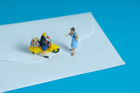 Miniature people toys conceptual photography. Mail postal courier delivery. Postman courier with...