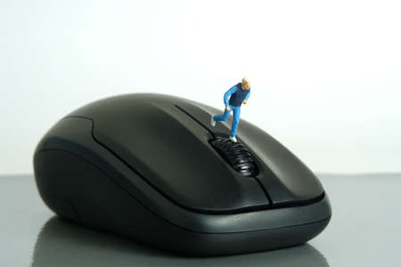Miniature people toy figure photography. Creative concept. A young men runner jogging above black mouse, isolated on white background. Image photoの写真素材
