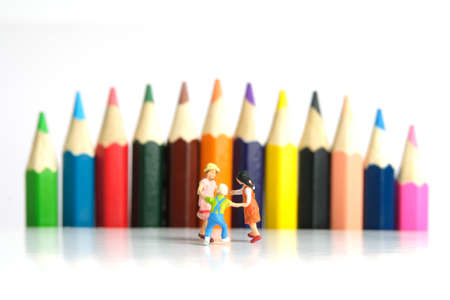 Miniature people toy figure photography. Drawing class concept. A group of kids playing on colorful pencil, isolated on white background. Image photoの写真素材