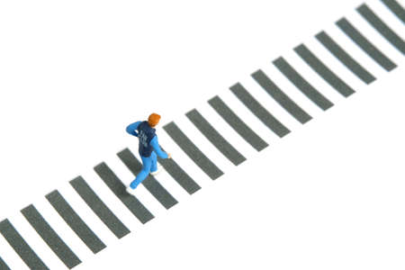 Miniature people toy figure photography. A young men running on crosswalk, isolated on white...