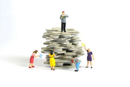Miniature people toy figure photography. A group of student standing above puzzle jigsaw stack, isolated on white background. Image photoの写真素材