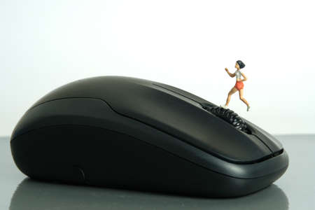 Miniature people toy figure photography. Creative concept. A girl runner jogging above black mouse, isolated on white background. Image photoの写真素材