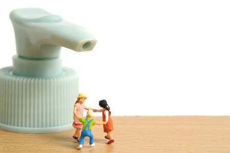 Miniature people toy figure photography. Health protocol on pandemic concept. A group of kids playing with head sanitizer bottle. Image photoの写真素材