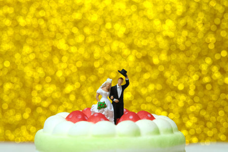 Bride and groom standing above cake with golden bokeh defocused blurry background. Image photoの写真素材