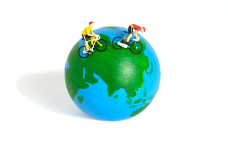 Miniature people toy figure photography. World bicycle day or tour around the world concept. A biker cycling above earth globe, isolated on white background. Image photoの写真素材