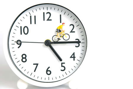 Miniature people toy figure photography. Cycling schedule concept. A biker cycling above clockwise, isolated on white background. Image photoの写真素材
