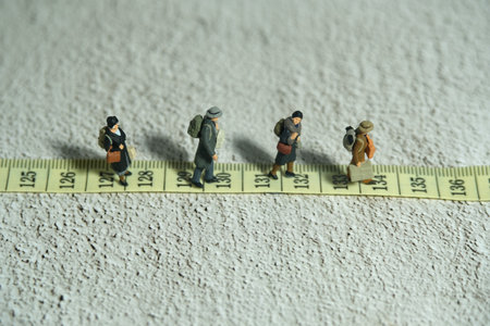 Miniature people toy figure photography. A group of person walking above measuring tape. Distance...