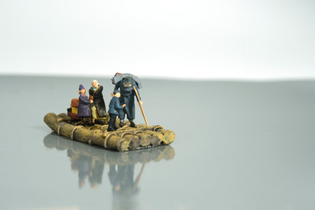 Miniature people toy figure photography. An old man refugees with crutch riding the raft alone, escape from conflict area to save place because of war. Image photoの写真素材