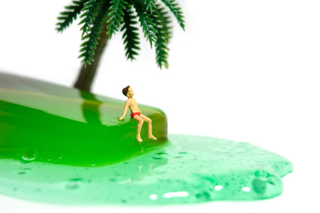 Miniature people toy figure photography. Creative summer vacation concept. A kid sitting and relaxing above green watermelon melting ice cream. Isolated on white background. Image photoの写真素材