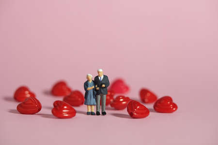 Miniature people toys conceptual photography. Man and women elderly standing in the center of heart shape. Couple in love concept. Image photoの写真素材