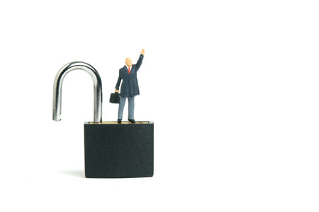 Miniature people toy figure photography. Idea creativity unlock concept. A businessman standing above closed padlock while raise his hand. Isolated on white background. Image photoの写真素材