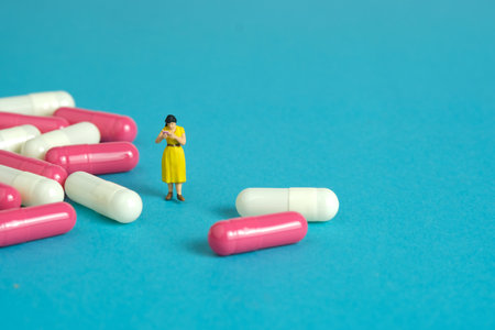 Miniature people toy figure photography. A girl student standing in the middle of drug pill reading the ingredient. Image photoの写真素材