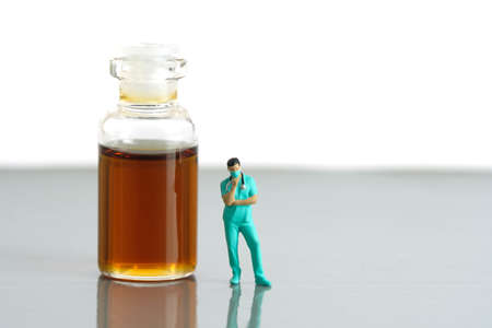 Miniature people toy figure photography. Urine test concept. A nurse standing in front of ampoule...