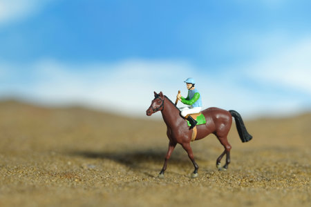 Miniature people toy figure photography. A jockey man riding horse at farm, sand desert land field. Image photoの写真素材