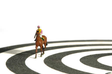 Miniature people toy figure photography. Jockey men riding horse on a racetrack from dartboard. Isolated on white background. Image photoの写真素材