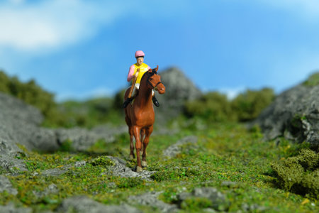 Miniature people toy figure photography. A jockey man riding horse at mountain hill for training. Image photoの写真素材