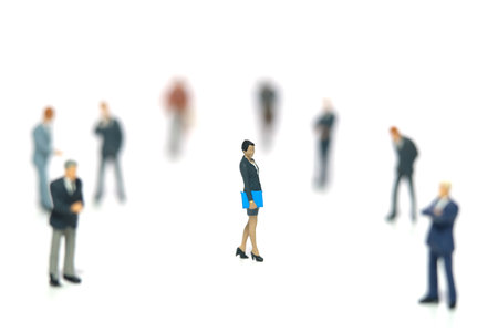 Miniature people toy figure photography. Women empowerment concept. A businesswoman standing in the middle of male people crowd. Isolated on white background. Image photoの写真素材