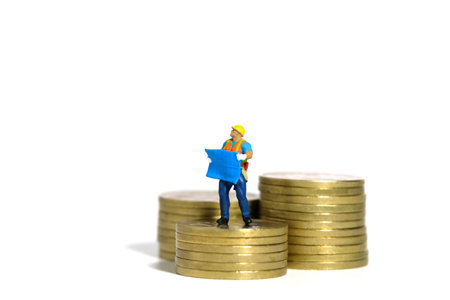 Miniature people toy figure photography. Project budget concept. A construction worker with...