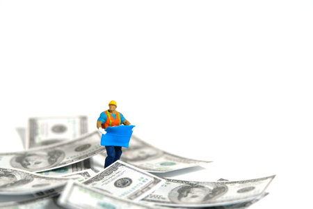 Miniature people toy figure photography. Project budget concept. A construction worker with...