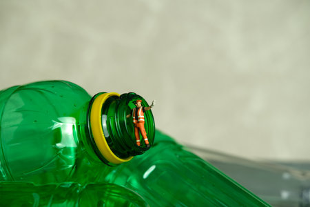 Miniature people toy figure photography. Cleaning worker with trash bin walking between drink bottle plastic. Image photoの写真素材