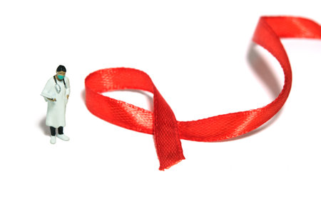 Miniature people figure toys photography. World AIDS Day awareness day concept. Girl woman doctor standing beside red ribbon. Isolated on white background. Image photoの写真素材