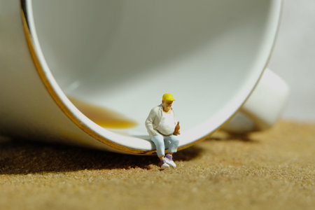 Miniature people toy figure photography. Fat men worker take a break rest sitting in front cup of coffee. Image photoの写真素材