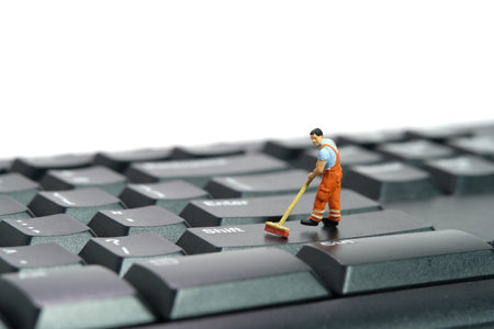 Miniature people toy figure photography. Sweeper workers cleaning mechanical keyboard using broom,...