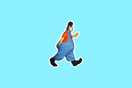 Miniature people toy figure photography. Side view full body of a clown wearing tie and jumper suit. Isolate on blue background. Image photoの写真素材