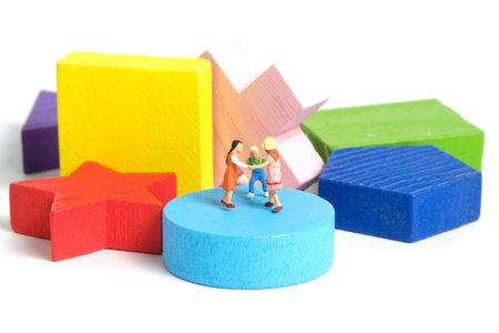 Miniature people toy figure photography. Fun learning concept. Kids play together above Montessori wooden puzzle. Isolated on white background. Image photoの写真素材