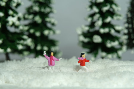 Miniature people toy figure photography. Winter holiday. Kids brother and sister playing snowball throwing in the pine fir forest. Image photoの写真素材