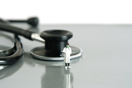 Miniature people toy figure photography. Health concept. A women doctor while standing with stethoscope on a desk. Isolated white background. Image photoの写真素材