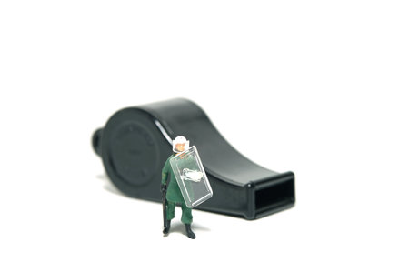 Miniature people toy figure photography. Justice collaborator and whistleblower protection concept. A military anti riot armored army with black whistle. Isolated on white background. Image photoの写真素材