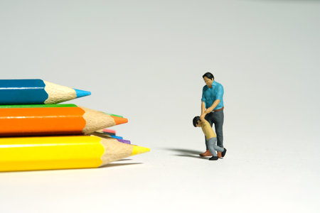 Miniature people toy figure photography. Toddler want to play coloring and drawing concept. A father and son standing in front of pencil color. Image photoの写真素材