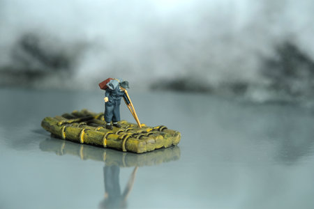 Miniature people toy figure photography. An old man refugees with crutch riding the raft alone, escape from conflict area to save place because of war. Image photoの写真素材