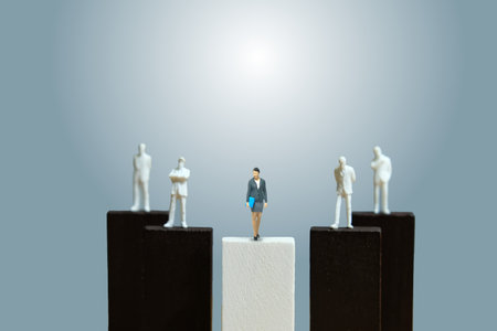 Miniature people toy figure photography. Businesswoman leader concept. A businesswoman and businessman shadow standing above podium. Image photoの写真素材