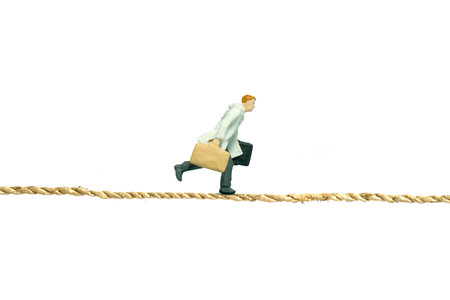 Miniature people toy figure photography. A businessman wearing coat running above tight rope...