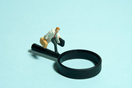 Miniature tiny people toy figure photography. A man wearing with coat running above magnifier glass....