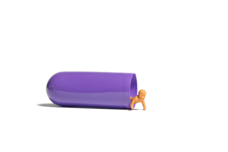 Miniature tiny people toy figure photography. A newborn baby crawling out from inside of purple medicine pill tablet. Isolated on white background. Image photoの写真素材