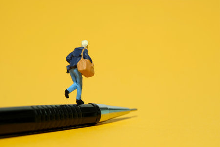 Miniature tiny people toy figure photography. A college student running above pencil carrying bag....