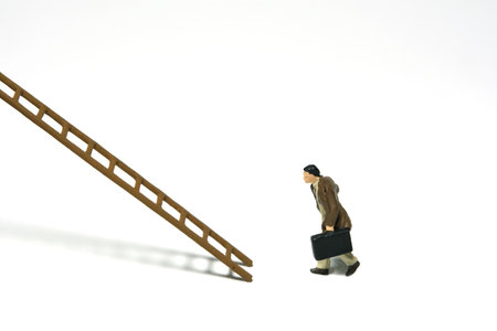 Miniature people toy figure photography. Success career stair concept illustration. A businessman running toward wooden ladder, isolated on white background. Image photoの写真素材